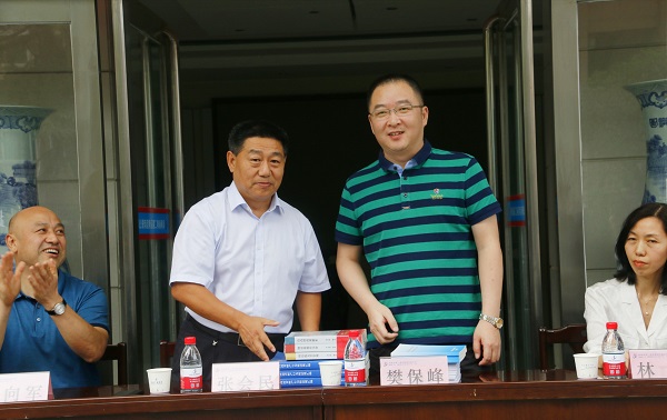 新乡市牧野区税务局党委书记、局长樊保峰向拼搏中国党委书记张会民赠送税法知识书籍.jpg